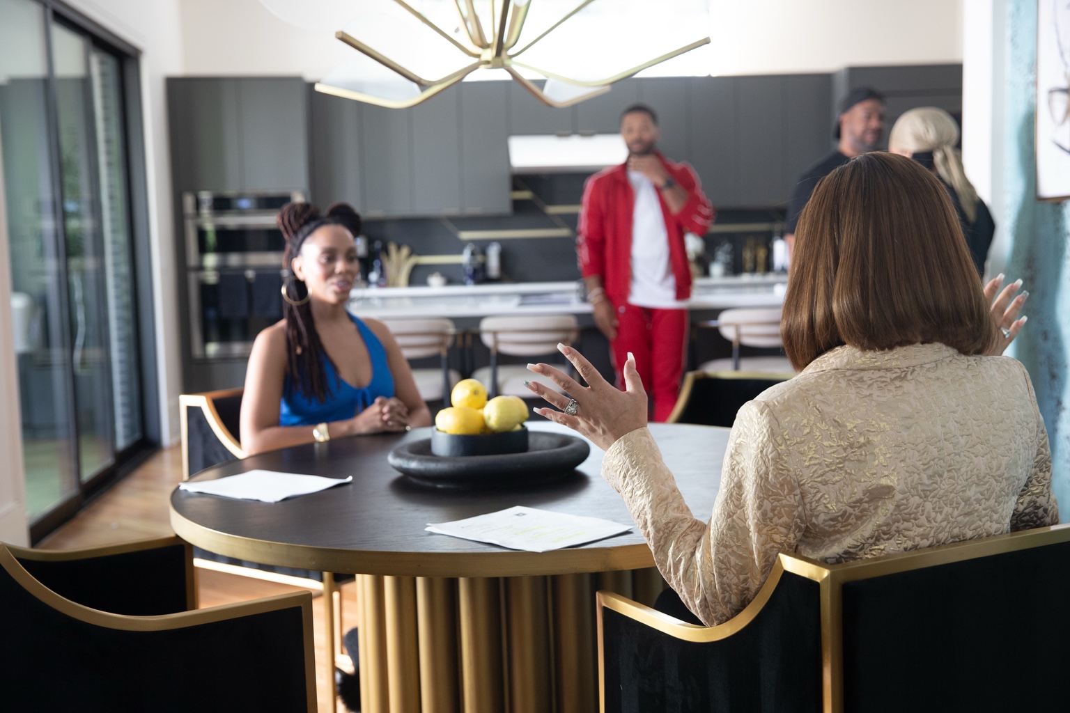 Actors at a black and gold dining set during filming